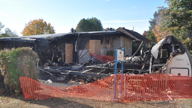 Fire outside a house: damaged recreational vehicle, cars and motorcycles